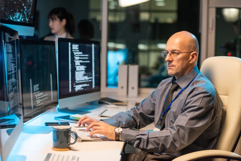 Serious businessman looking through data on computer screen