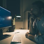 Man focused on reading computer codes. Programmer working late from his home office